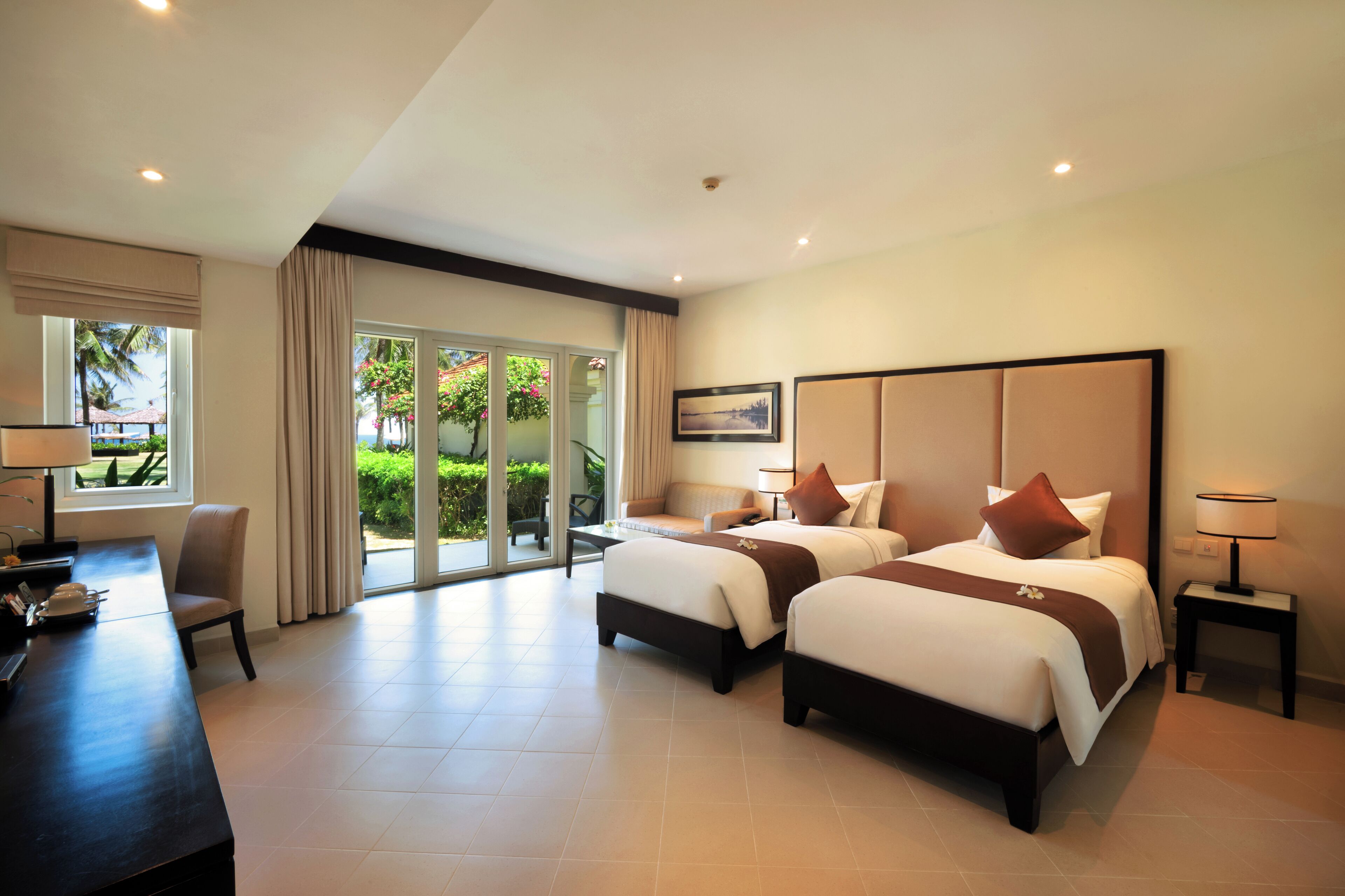 Une chambre d’hôtel avec deux lits, un bureau et une vue sur l’extérieur.