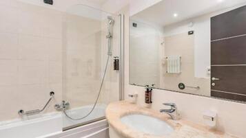 Un bagno moderno con cabina doccia in vetro, una vasca freestanding e un lavabo in marmo con uno specchio sopra.