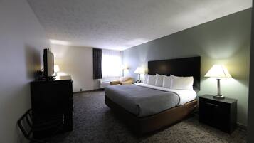 Camera d'albergo con un letto grande, comodini con lampade, una scrivania con sedia e una televisione.