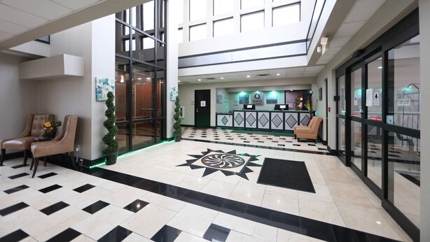 Un hall de hotel con mostrador de recepción, zona de estar y un diseño decorativo en el suelo.