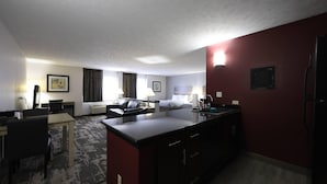 Habitación de hotel con kitchenette, comedor, cama y baño.