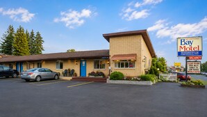 A motel with a parking lot, a sign indicating air conditioning, and a signboard advertising the motel.