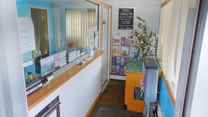 A reception area with a counter, a bulletin board, and a sign with hotel information.