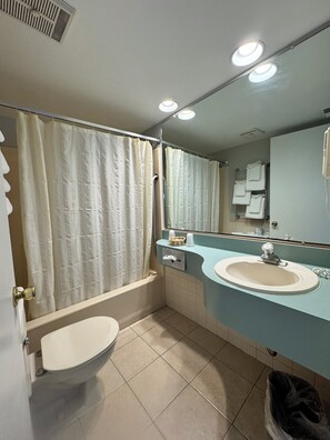 A bathroom with a bathtub, toilet, sink, and a mirror. - Wild Dunes Inn (Ocean City)
