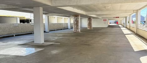 Eine leere Tiefgarage mit Betonpfeilern, einem Schild mit der Aufschrift 'Freihalt vermeiden' und einem Stoppschild.
