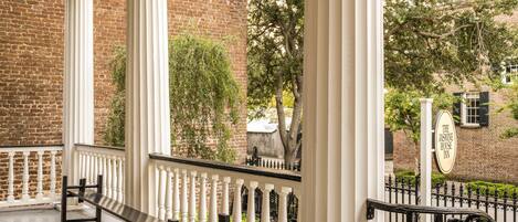 A covered porch with white columns and a bench.