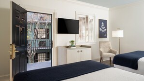 A hotel room with a bed, a chair, a desk, a TV, and a door leading outside.