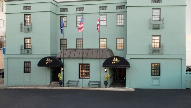 A light blue building with a black awning, American and British flags, and a sign that reads "Antigo Hotel."