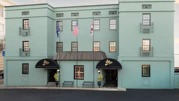 Stylish two-story hotel with a symmetrical design and central entrance, featuring a black awning and two benches outside.