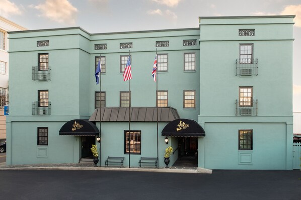 A light blue building with a black awning, American and British flags, and a sign that reads "Antigo Hotel."