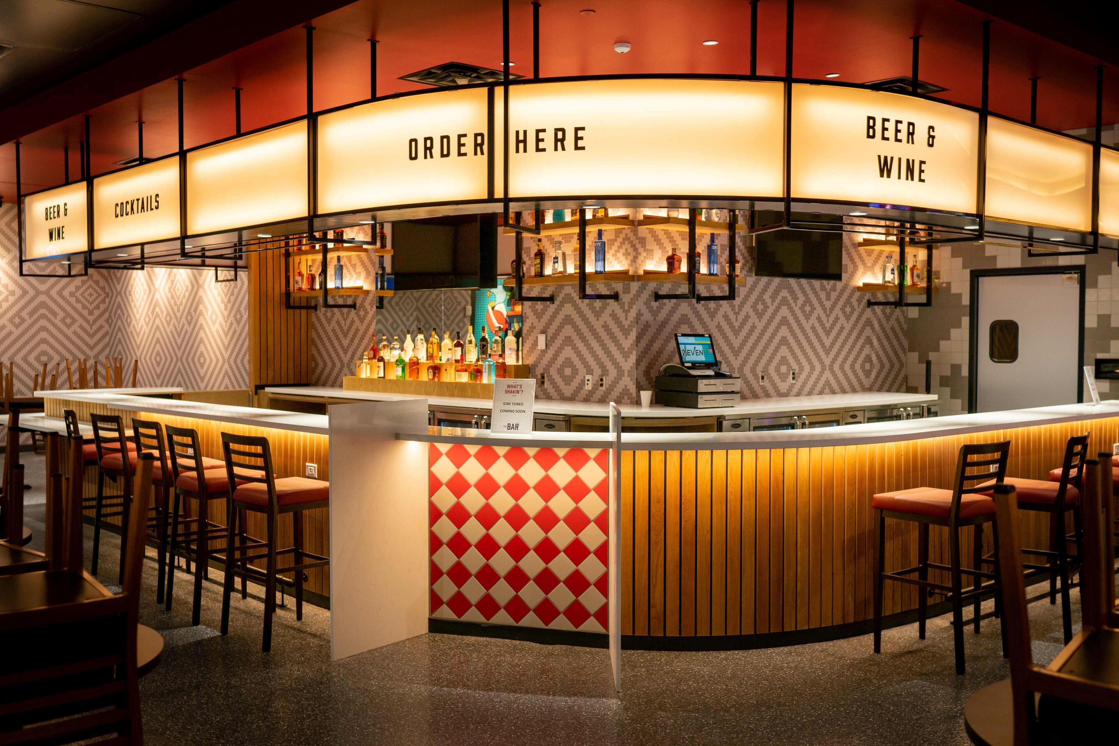 A bar area with a counter, stools, and a sign indicating beer and wine service.