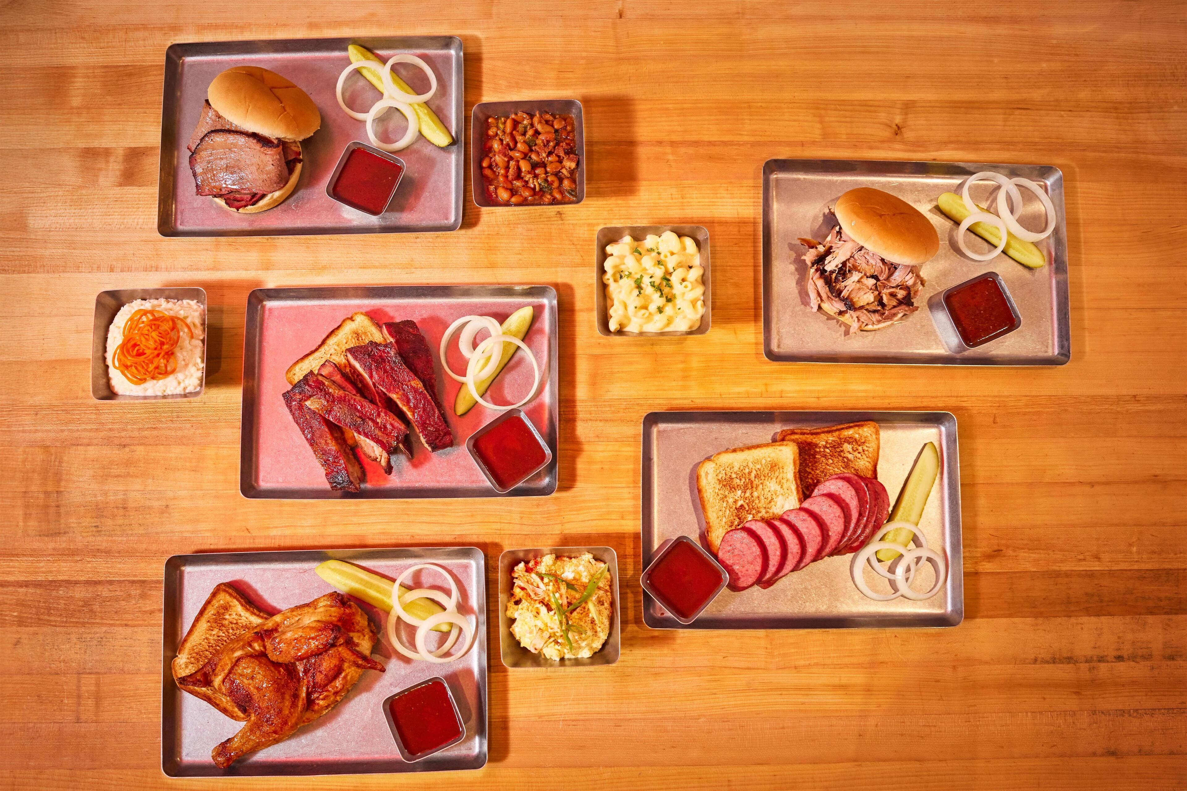 Une table en bois sur laquelle sont disposés divers aliments, présentés sur des plateaux en métal.
