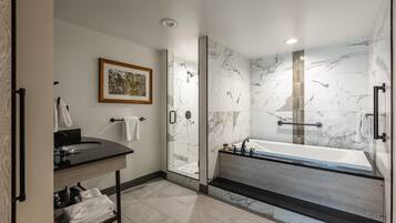 A modern bathroom with a glass-enclosed shower, a freestanding bathtub, and a vanity with a sink and towel rack.