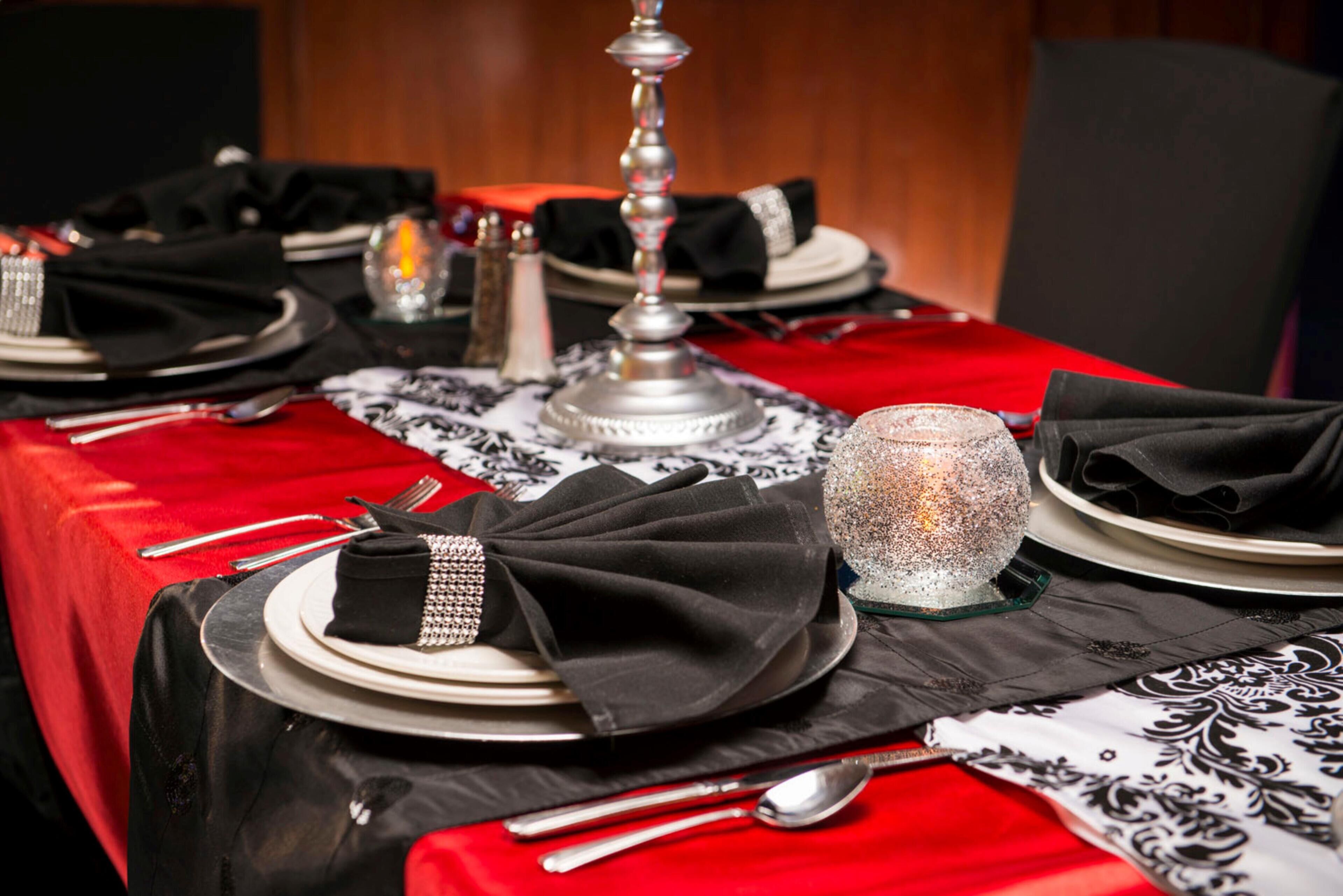 A table set with black and white tablecloths, silverware, and a decorative glass centerpiece.