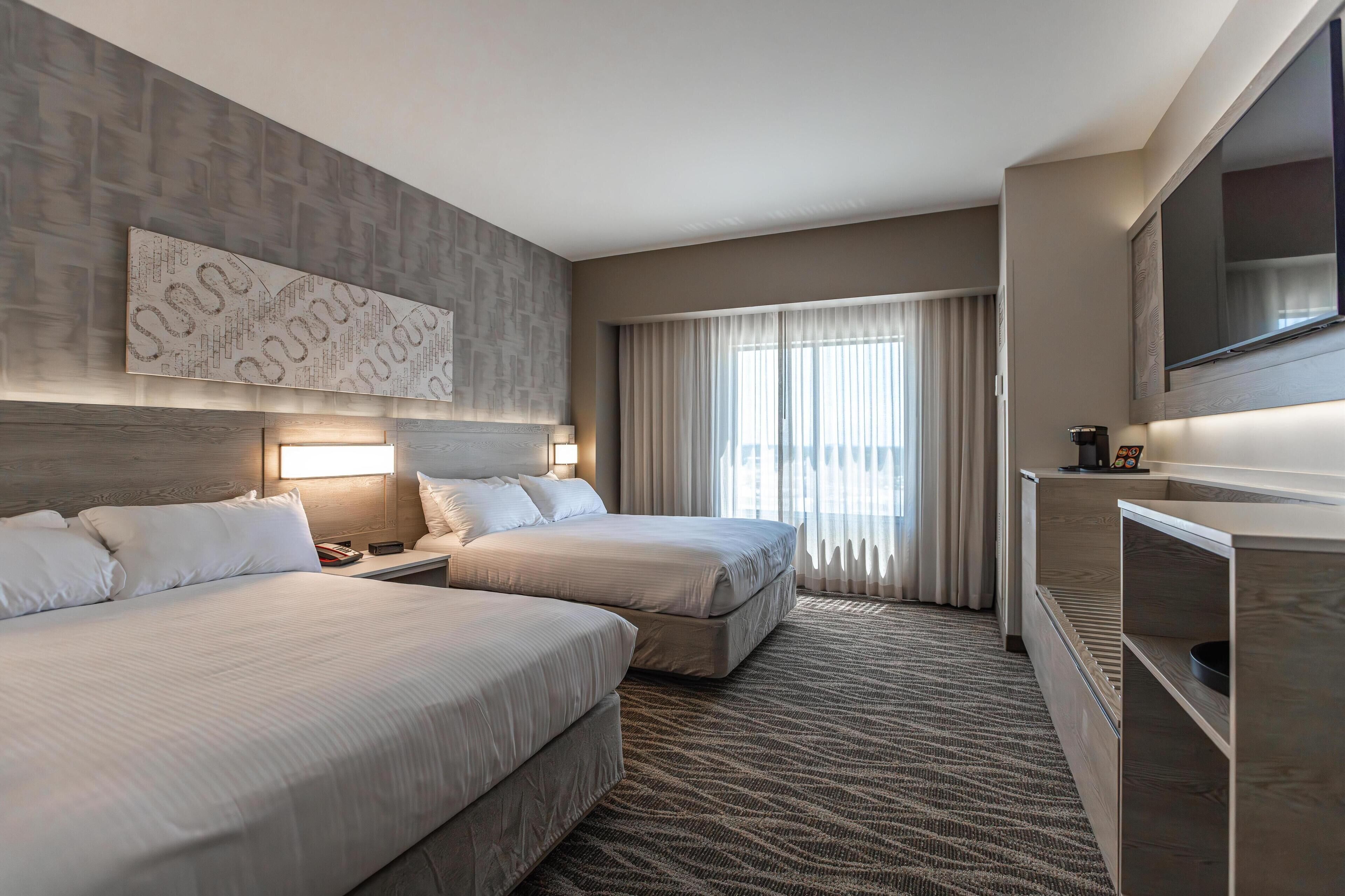 A hotel room with two beds, a large TV, and a wall-mounted artwork.