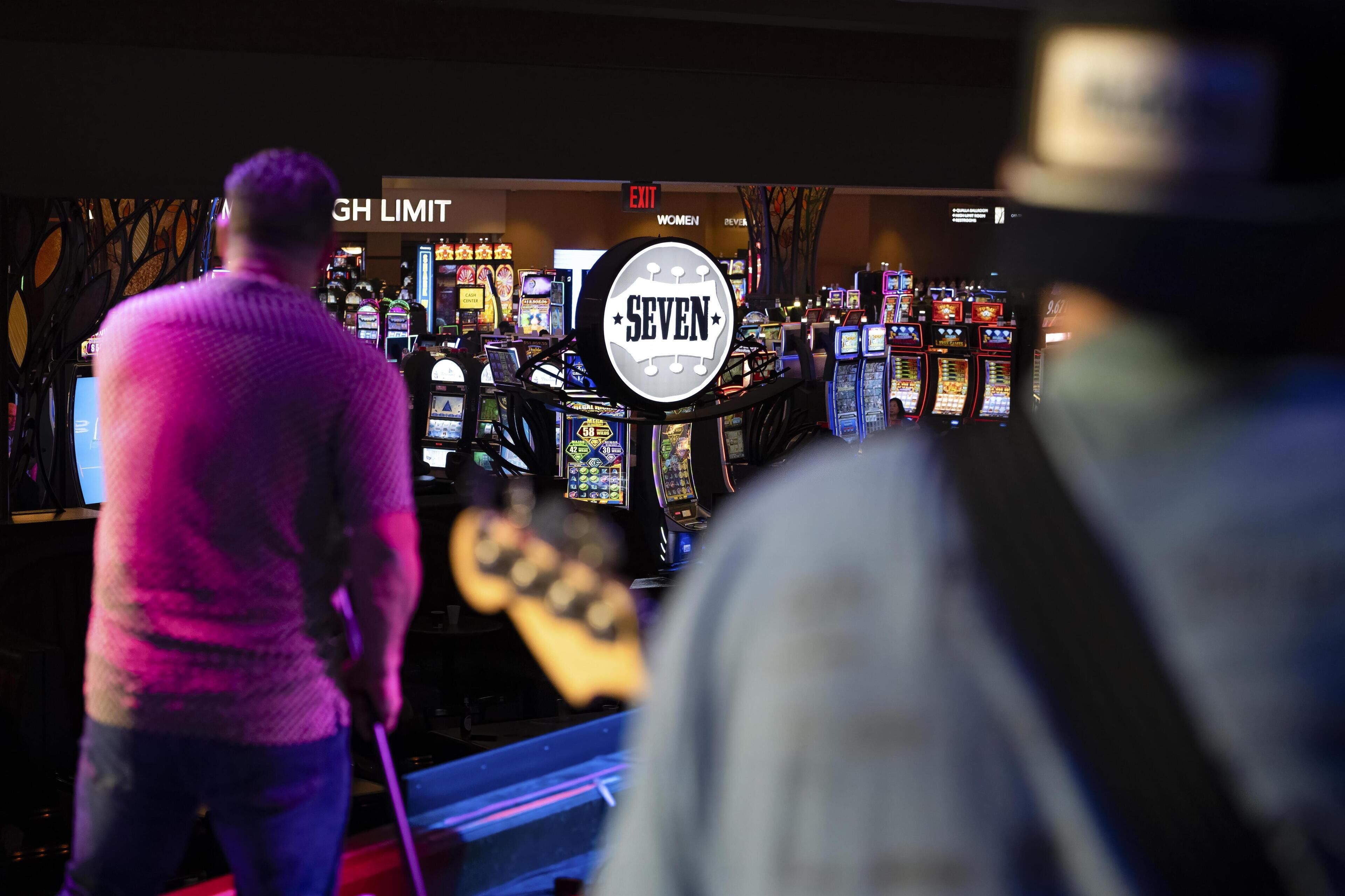 Un casino con numerosas máquinas tragamonedas y un llamativo letrero con el número 'SEVEN'.