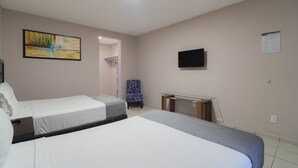 Habitación de hotel con dos camas, un escritorio, una silla, un televisor y un cuadro en la pared.