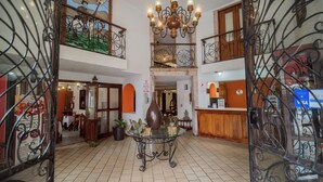 A hotel lobby with a glass-top table, a chandelier, and a painting on the wall.
