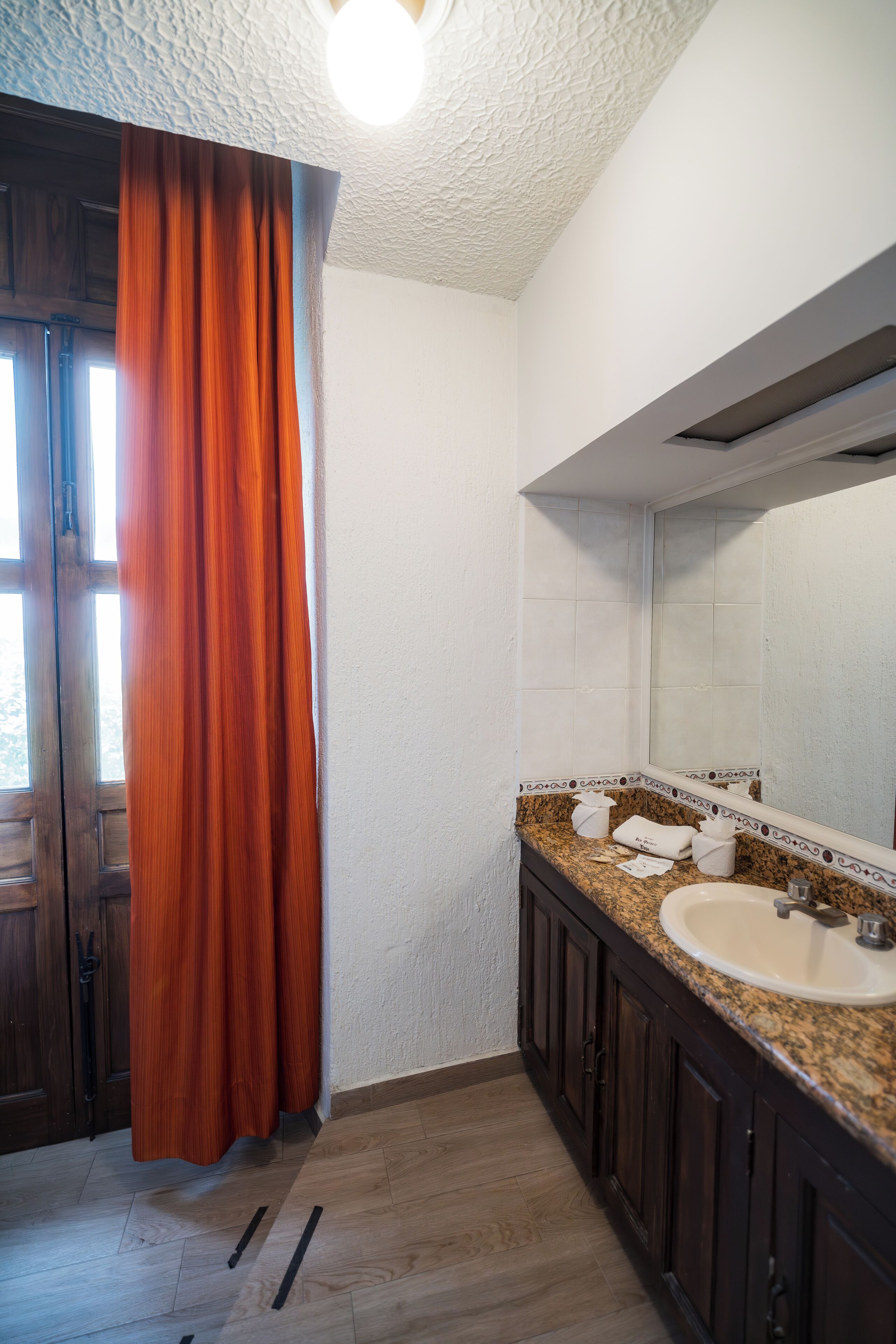 Une salle de bain avec un comptoir en granit, un lavabo, un miroir et un rideau de douche.