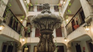 A courtyard with a central fountain, surrounded by balconies with plants.