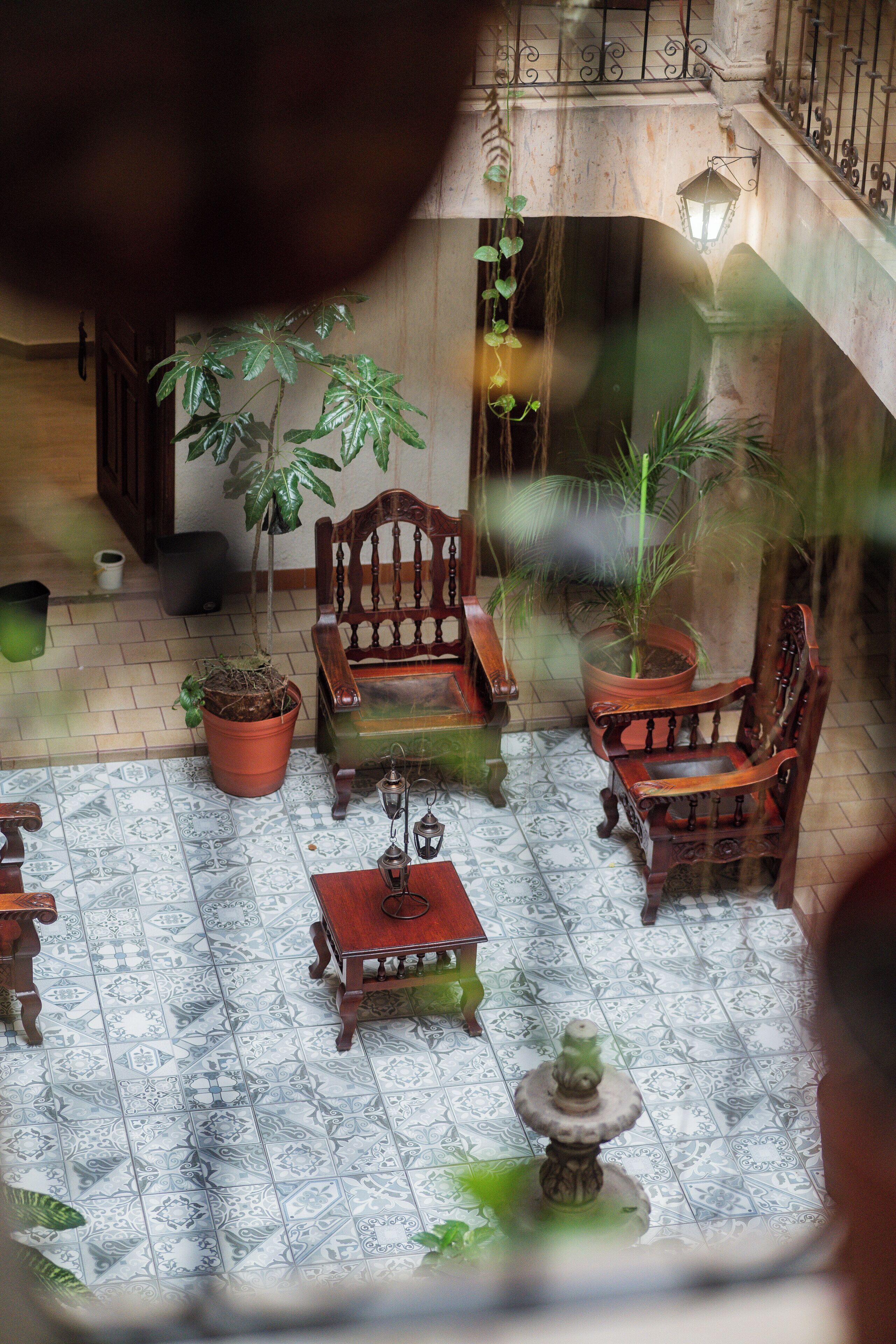 A courtyard with a wooden bench, a table, and potted plants.