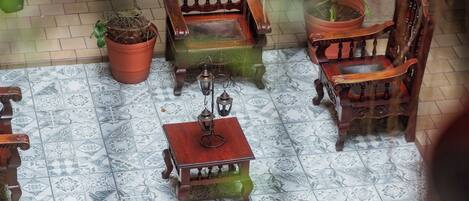 A courtyard with a wooden bench, a table, and potted plants.