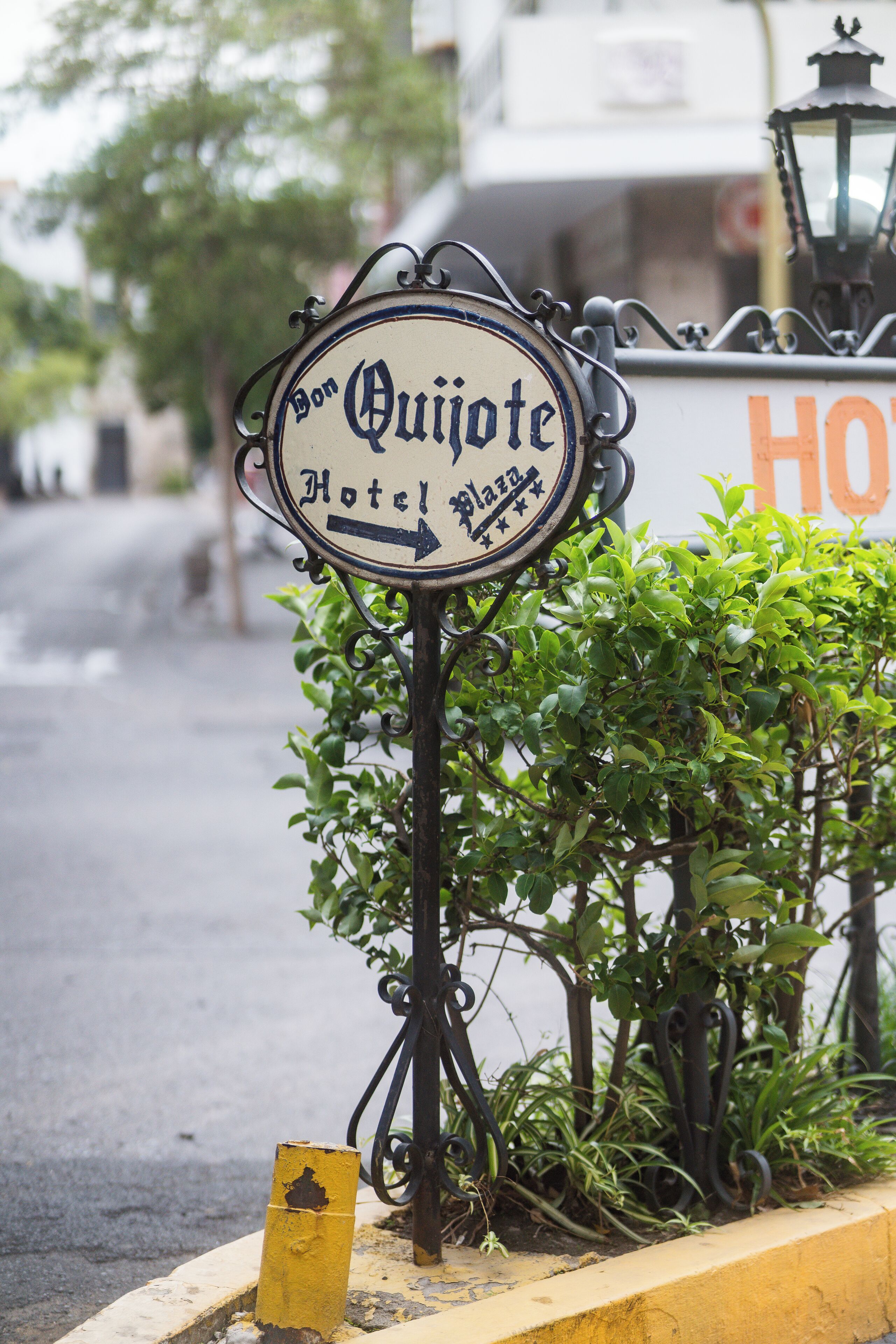 Une enseigne d’hôtel de style rétro, portant le nom « Bon Quiote Hotel » et une flèche pointant vers la droite.