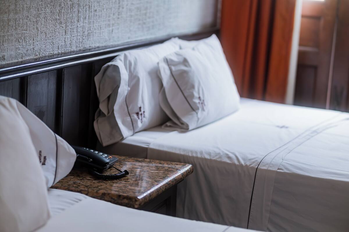 Une chambre d’hôtel avec un lit, une table de chevet avec un téléphone et une tête de lit.