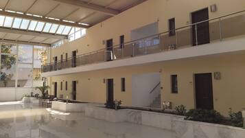 A spacious, multi-level atrium with a polished floor, large windows, and a balcony with glass railings.