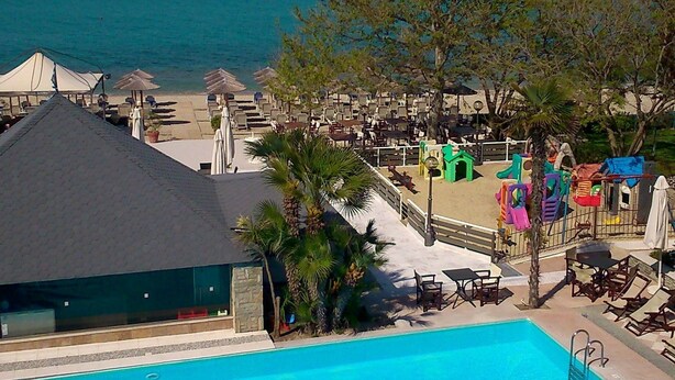 Zona de piscina con vista al océano, rodeada de sillones y sombrillas.