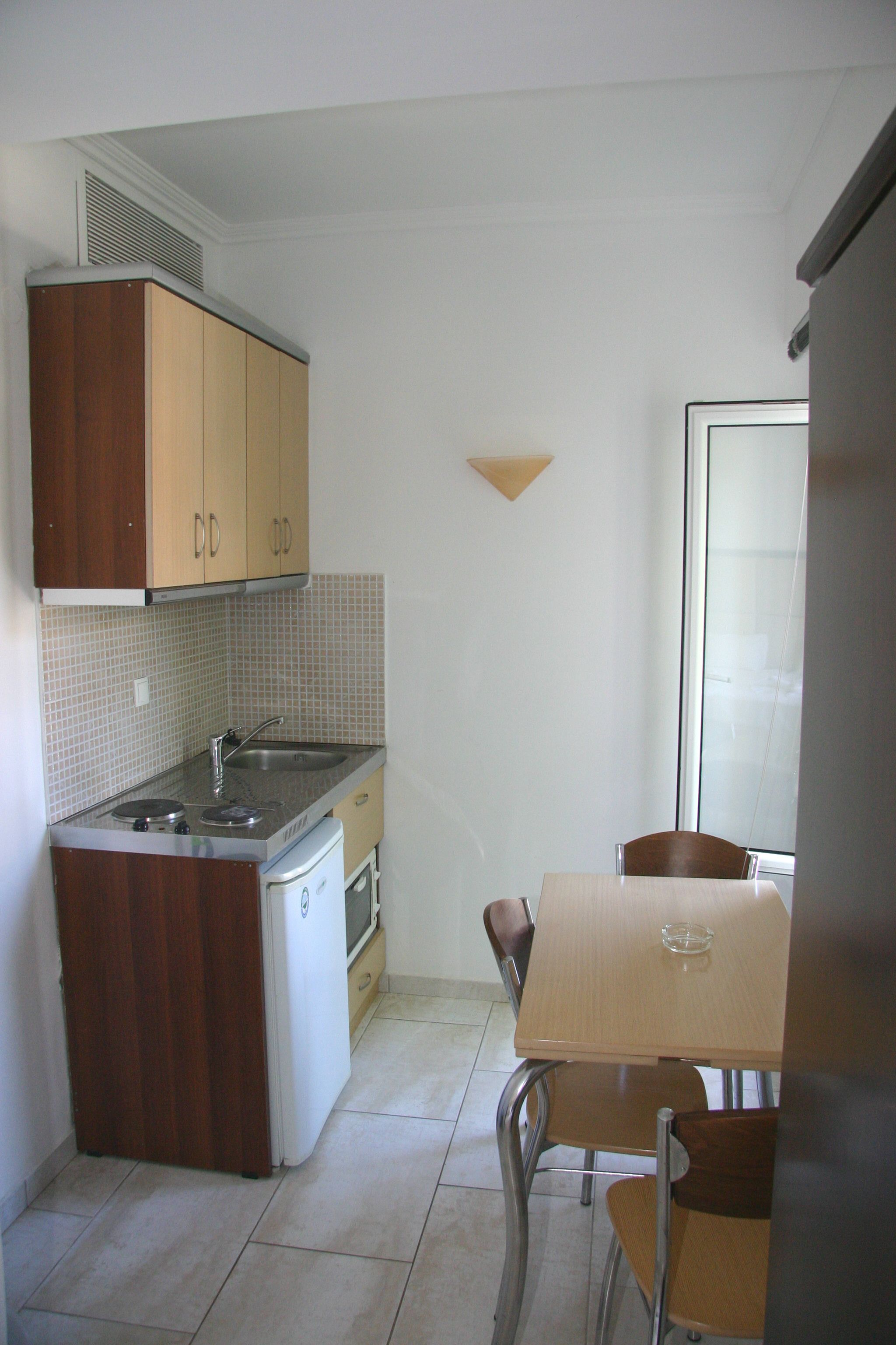 A compact kitchen with wooden cabinets, a built-in stove, and a small dining table with chairs.