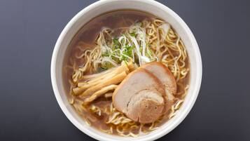 A bowl of ramen with noodles, pork, and vegetables.