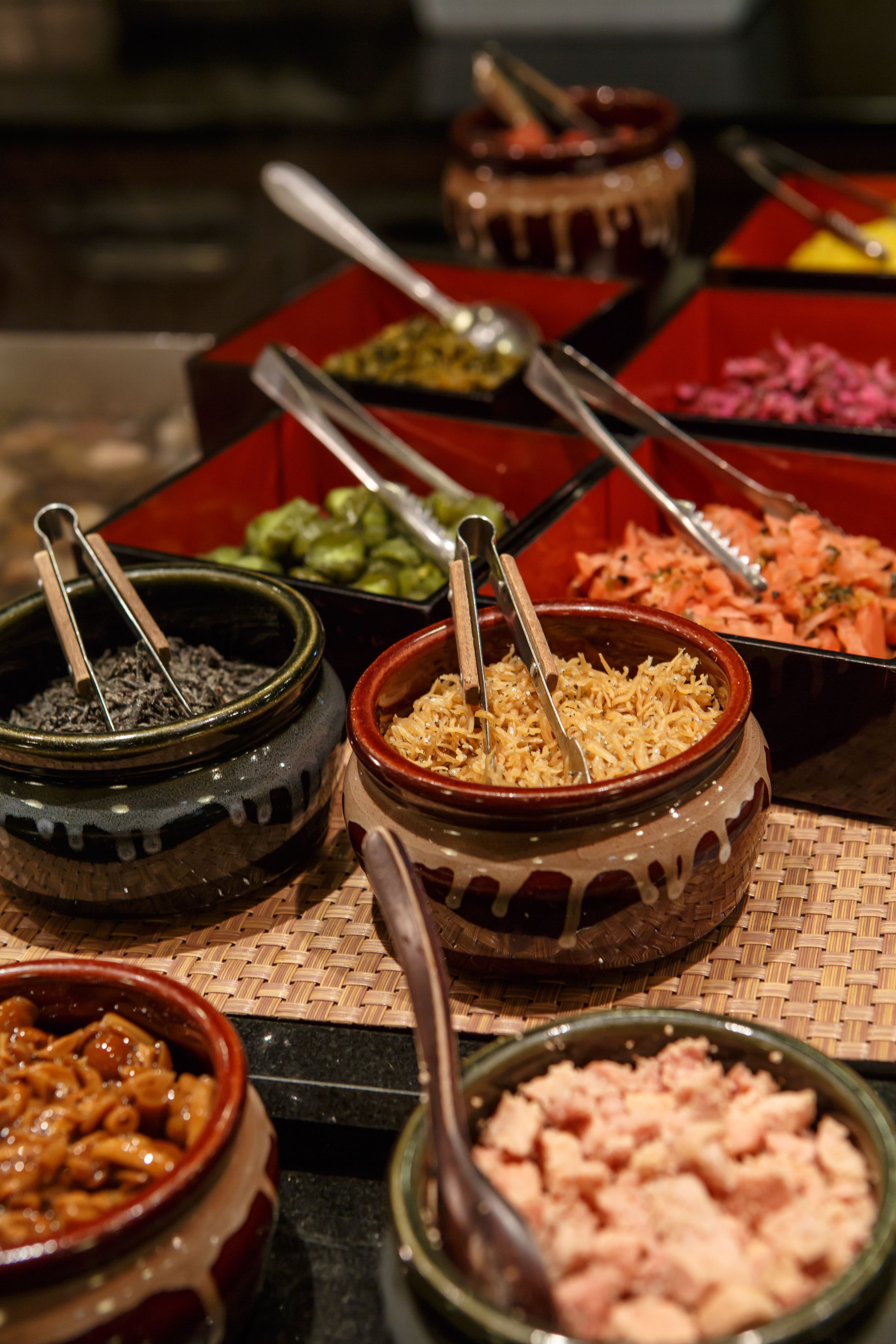 Un buffet proposant divers plats servis dans des bols en céramique, notamment des pâtes, de la viande et des légumes.