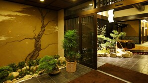 Un interior japonès tradicional amb un jardí de roques, bonsai i una porta corredissa de fusta.