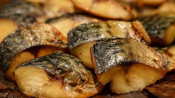 Une vue rapprochée d’un poisson cuit, dont la peau est croustillante, probablement préparé pour un repas.