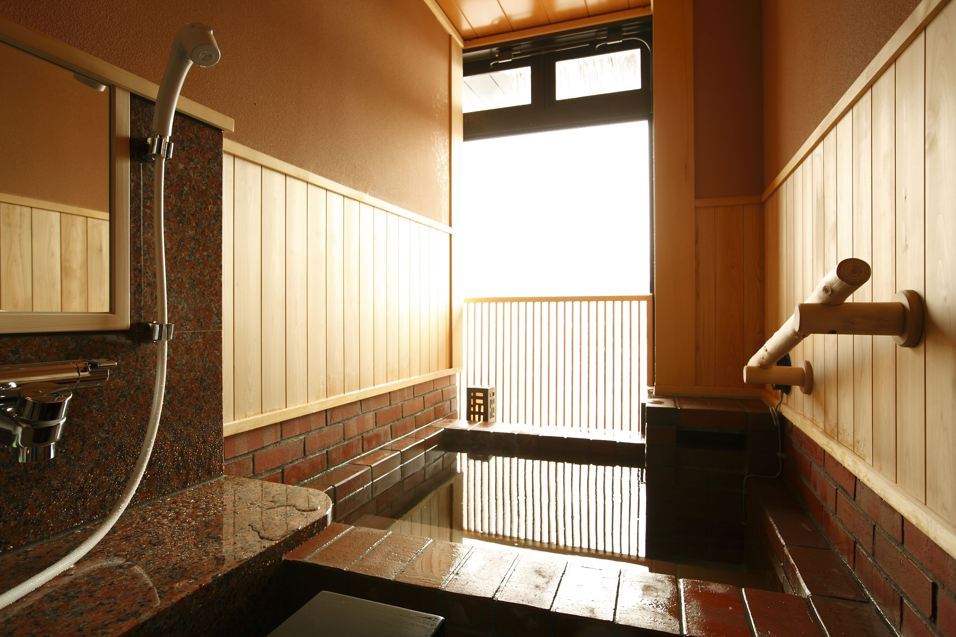 Un bagno con piano in granito, una doccetta e una panca di legno.