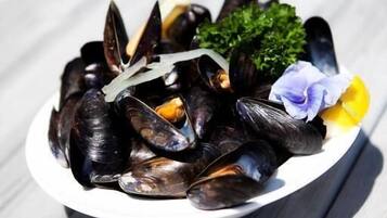 A plate of mussels with parsley and flowers on a wooden table.