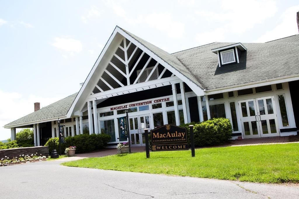 A building with a large entrance, a sign reading "MacAulay Conference Centre", and a welcoming sign.