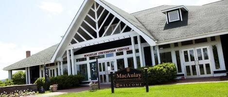 A building with a large entrance, a sign reading "MacAulay Conference Centre", and a welcoming sign.