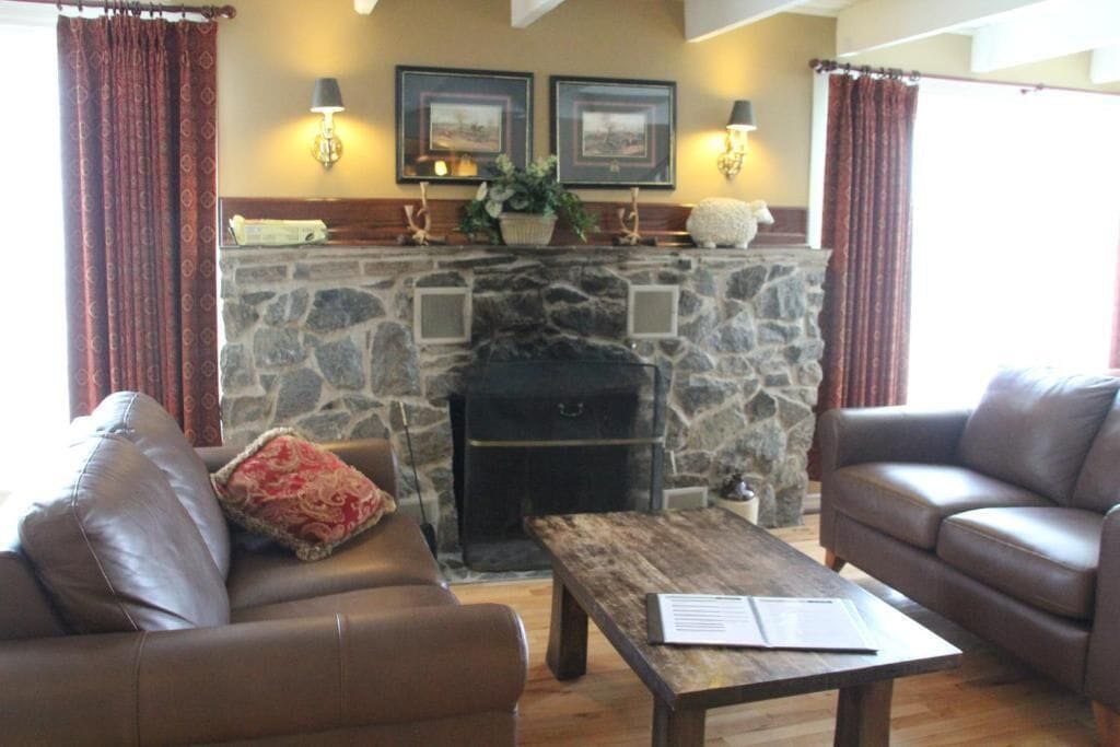 A cozy living room with a stone fireplace, leather sofas, and a wooden coffee table.