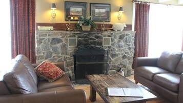 A cozy living room with a stone fireplace, leather sofas, and a wooden coffee table.