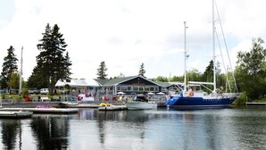 Un port de plaisance avec des bateaux amarrés, un bâtiment avec une enseigne et une étendue d’eau calme.