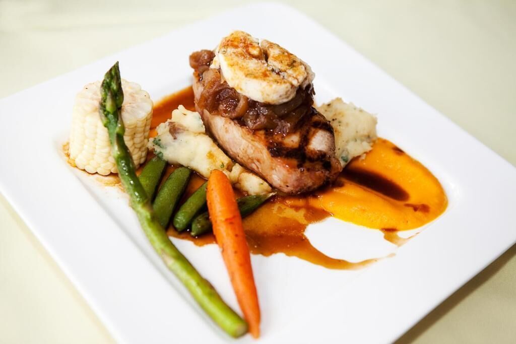 A plate of food with a piece of meat, vegetables, and sauce.