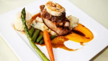 A plate of food with a piece of meat, vegetables, and sauce.