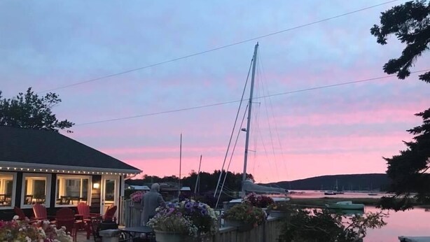 Un restaurant situé au bord de l’eau, avec une terrasse, offrant une vue sur un plan d’eau paisible et des bateaux.