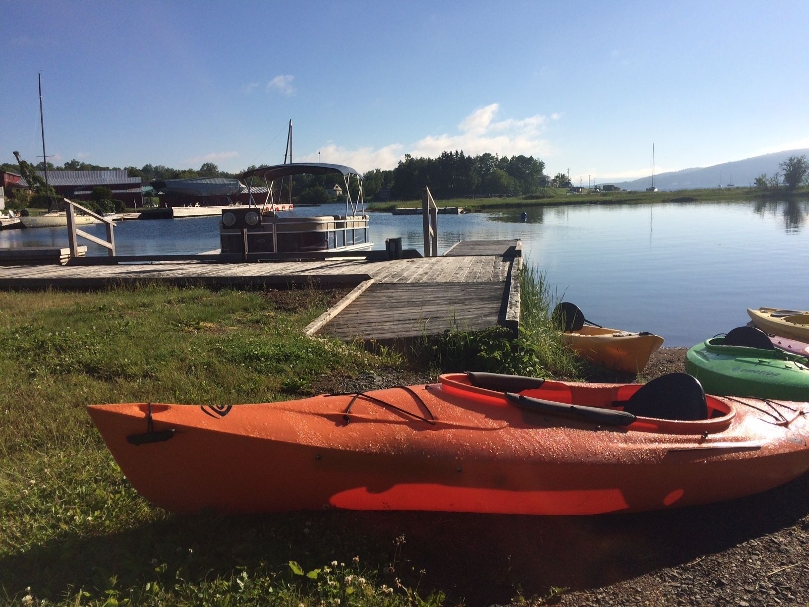 A calm lake with a dock and kayaks.