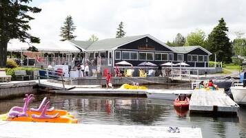A lakeside restaurant with outdoor seating and a dock with inflatable boats.