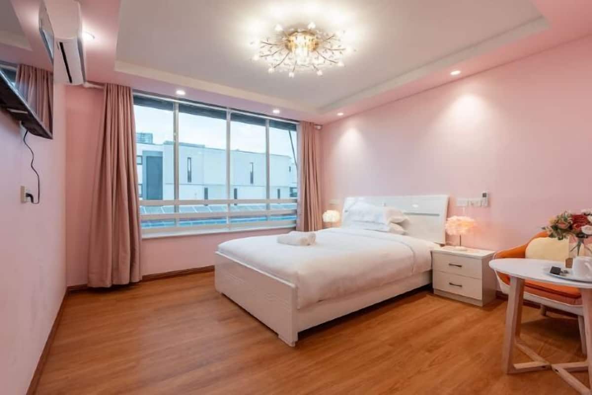 A bedroom with a bed, bedside table, and a window with curtains.