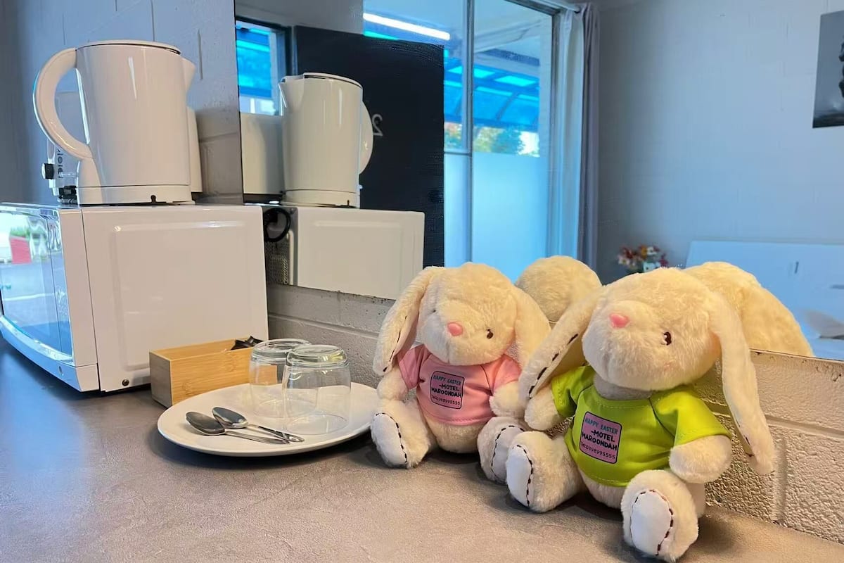 A kitchenette with a coffee maker, a plate with utensils, and two plush bunnies.