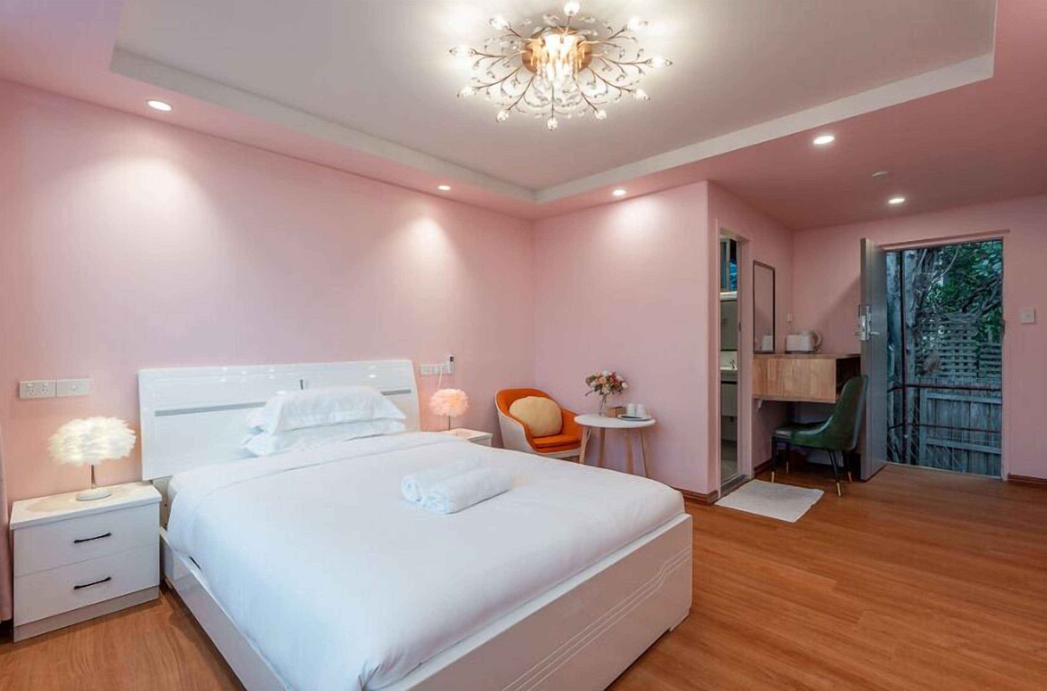 Une chambre à coucher avec un grand lit, une table de chevet, une chaise, une petite table et une porte donnant sur un balcon.